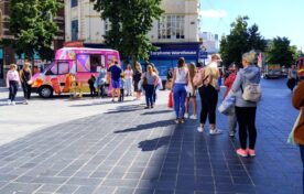 Long queue of consumers lining up at the custom-branded iMP promotional sampling van during the So Fragrance high-street roadshow