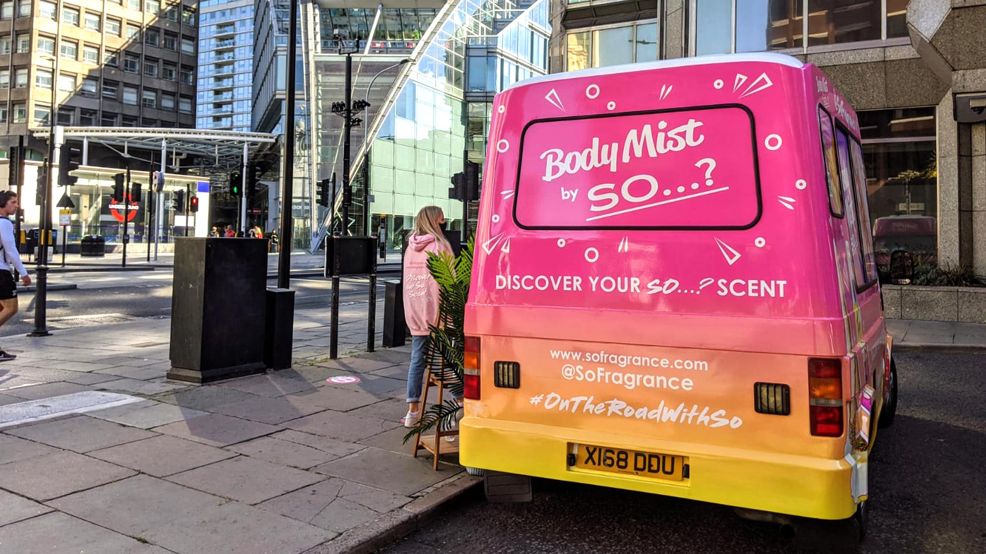 Rear view of a custom vinyl wrapped iMP sampling van featuring vibrant pink and orange branding for a cosmetics roadshow