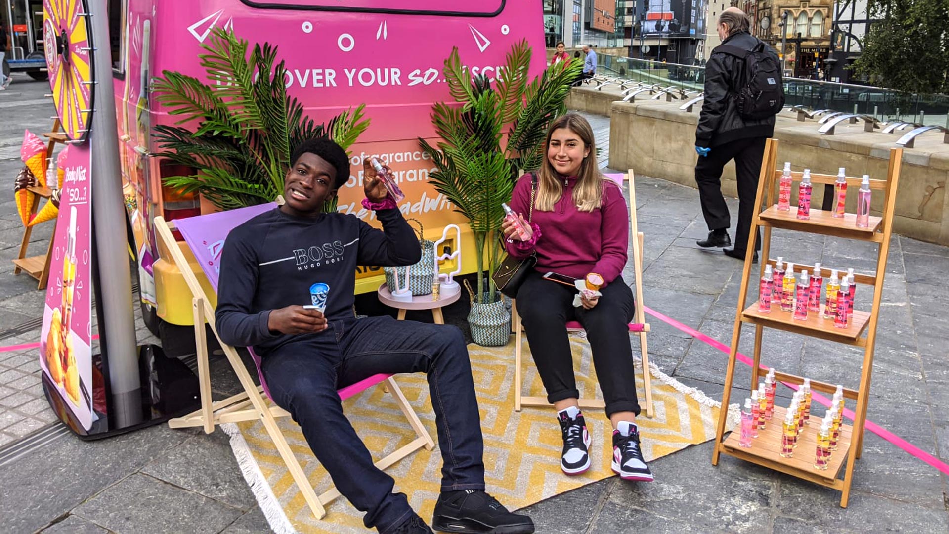 Consumers relaxing in branded deckchairs while sampling body mists at an outdoor iMP experiential event footprint