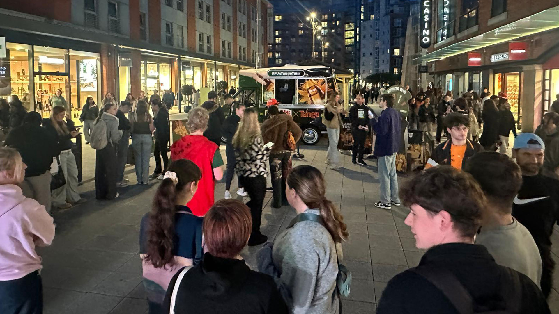 Crowd of students gathered around Papa Johns x Tango van taking photos and sharing on social media during campus sampling