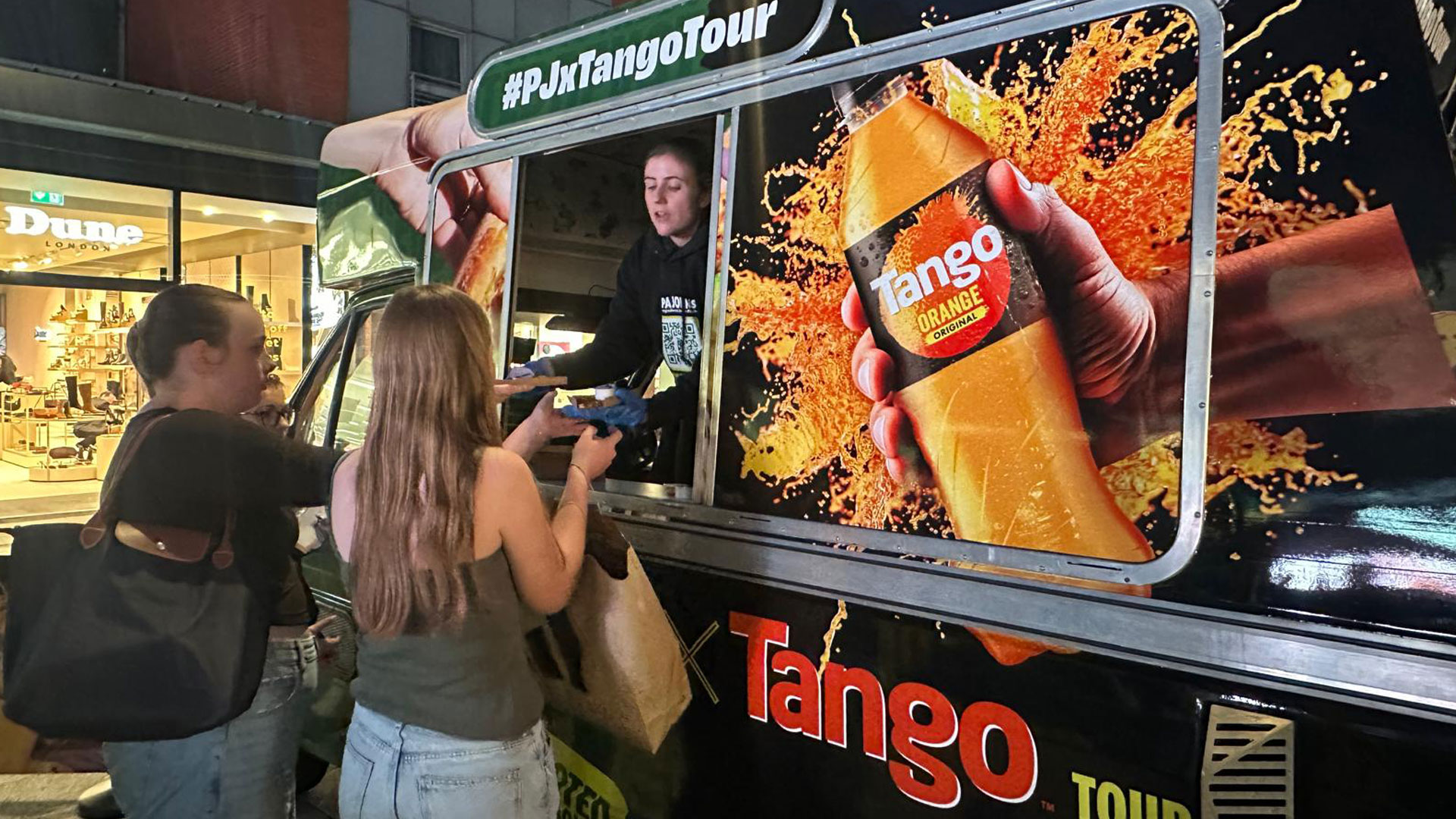 University students receiving free pizza and Tango cans from the iMP campus sampling van at student event