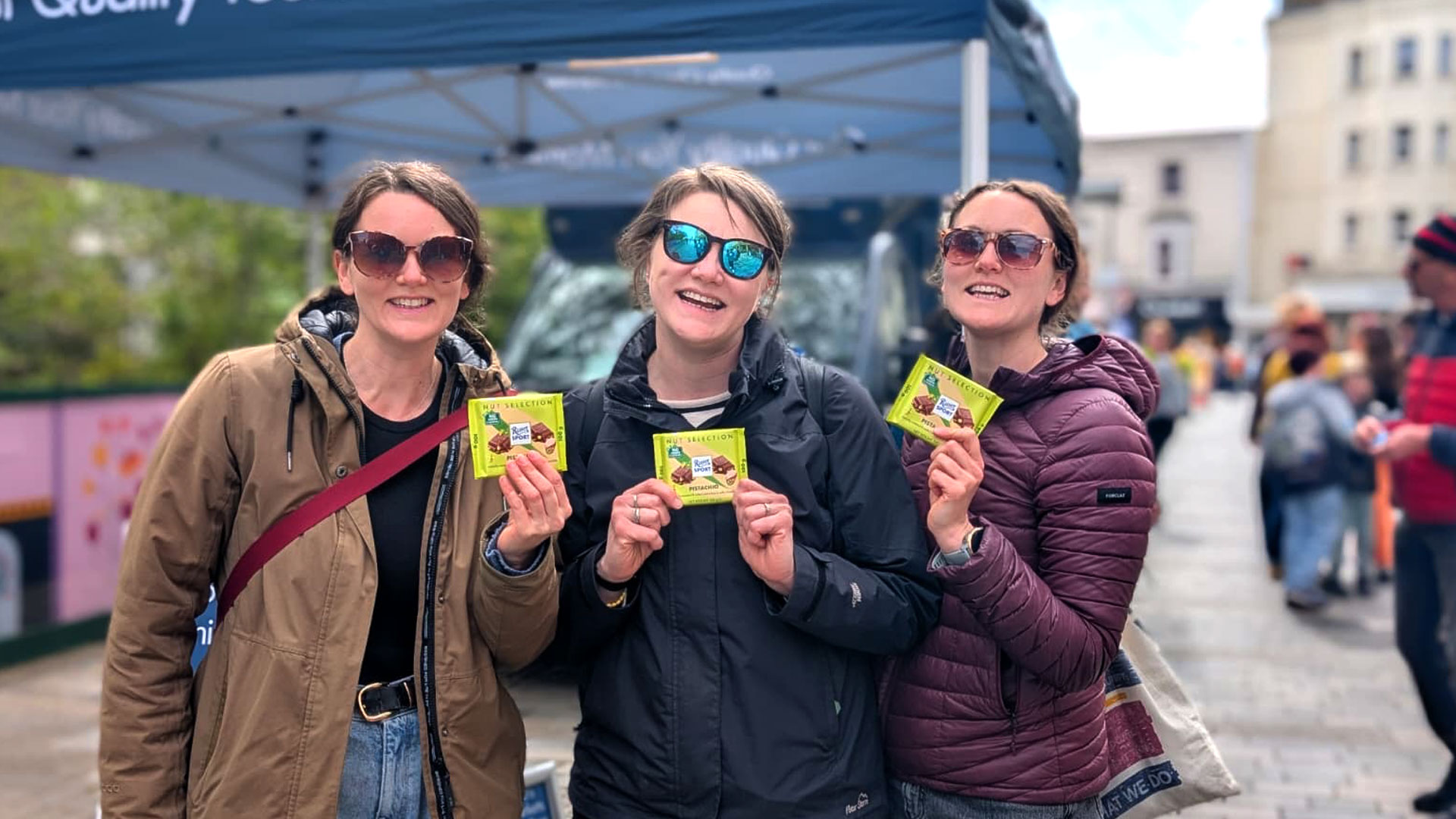Smiling consumers holding free Ritter Sport Pistachio 100g chocolate bars