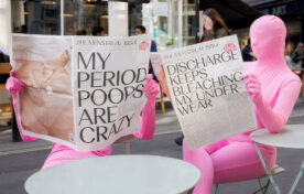 Two Flo App morph suit team reading fake newspapers in London